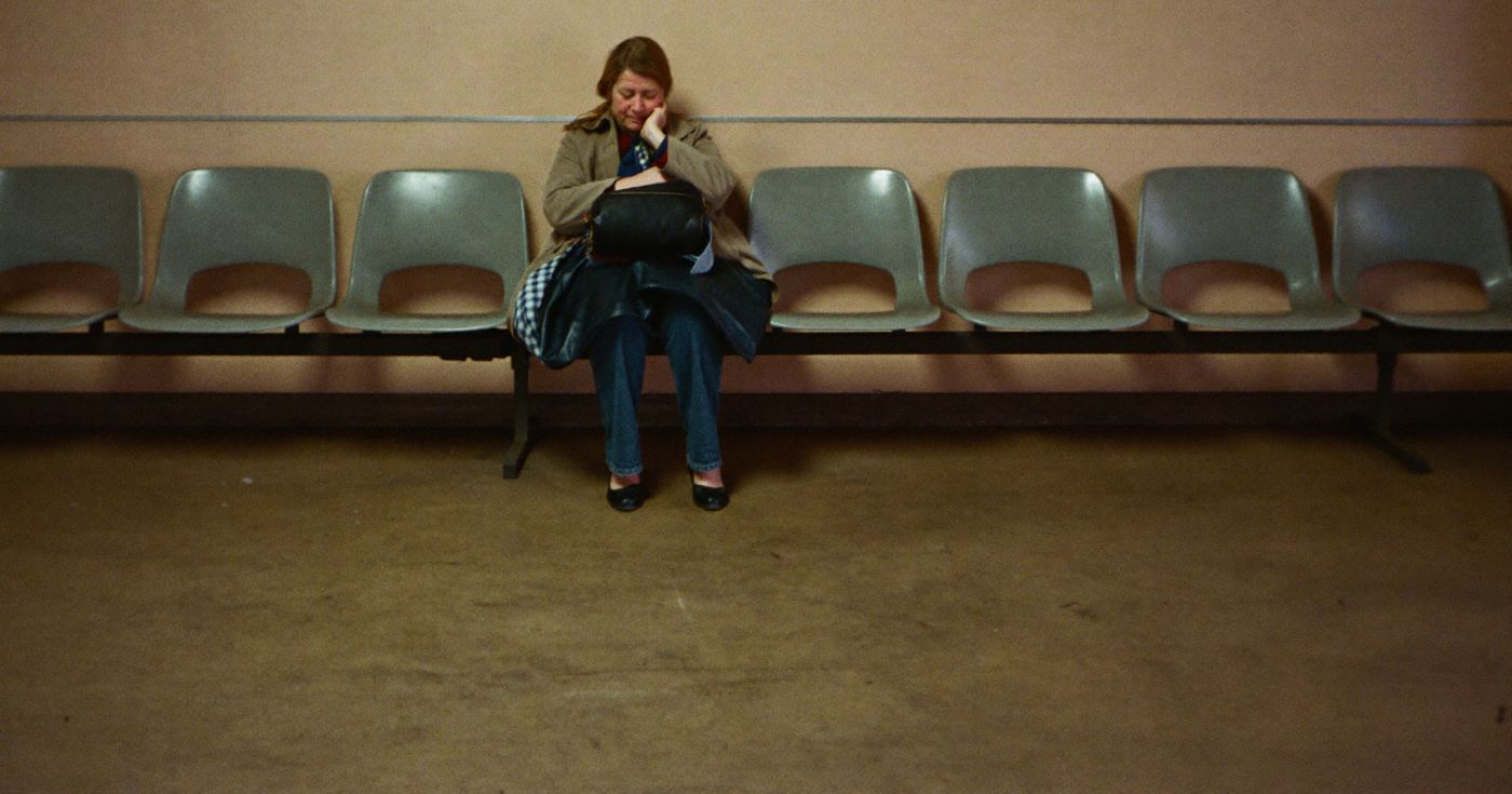 A woman sitting alone in a row of empty chairs